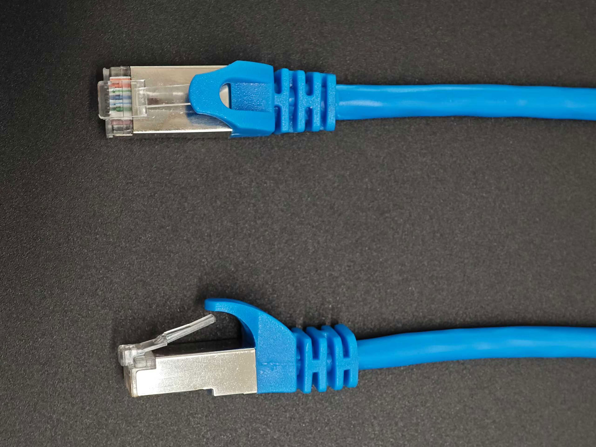 Blue network patch cable with metal-shielded modular plugs on a dark background